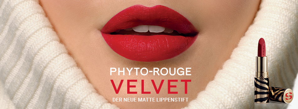 Nahaufnahme sinnlicher, perfekt geschminkter roter Lippen in einem weißen Rollkragenpullover. Text: 'PHYTO-ROUGE VELVET – Der neue matte Lippenstift'. Rechts ein luxuriöser Lippenstift in goldener Hülle mit Zebra-Muster.